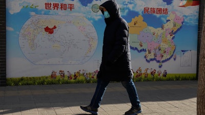 A man walks past a poster with the slogans 'World Peace' and 'Ethnic Unity' in Beijing, China on Jan. 11.