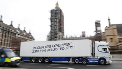 A shellfish export truck with a protest sign written across the trailer 'Incompetent Government Destroying Shellfish Industry' drives past the Palace of Westminster in London on Monday, Jan. 18 during a demonstration by British Shellfish exporters to protest Brexit-related red tape they claim is suffocating their business.