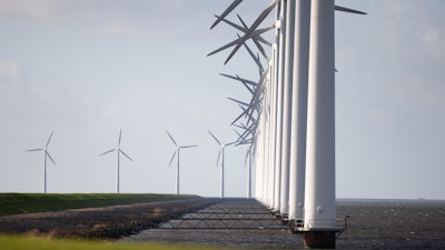 Wind turbines are seen on a dike near Urk, Netherlands, Friday, Jan. 22, 2021. A group of scientists, including five Nobel laureates, called Friday for more action to adapt the world to the effects of climate change, drawing comparisons with the faltering response to the coronavirus crisis, ahead of a major online conference on climate adaptation starting Monday and hosted by the Netherlands.