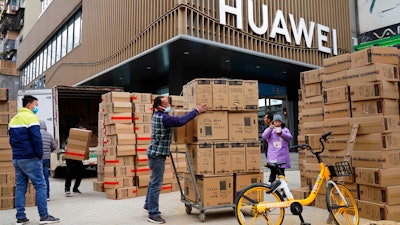 Workers move boxes of computers on a street in Wuhan, China, Jan. 16, 2021.