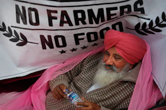 In this Dec. 14, 2020 photo, a protesting farmer rests on his tractor trailer blocking a highway with other farmers at the Delhi-Haryana border, on the outskirts of New Delhi, India.