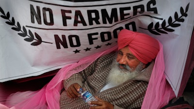 In this Dec. 14, 2020 photo, a protesting farmer rests on his tractor trailer blocking a highway with other farmers at the Delhi-Haryana border, on the outskirts of New Delhi, India.
