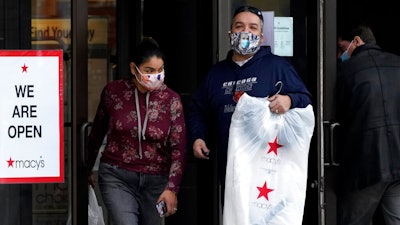 In this Dec. 19, 2020 file photo, Shoppers wear a mask as they leave a department store in Vernon Hills, Ill., The $600 stimulus checks got Americans shopping again. After three months of declines, retail sales soared a seasonally adjusted 5.3% in January from the month before, the U.S. Commerce Department said Wednesday, Feb. 17, 2021.