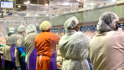 Tyson Foods workers wear protective masks and stand between plastic dividers at the company's Camilla, Georgia poultry processing plant.