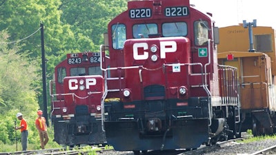 In this May 23, 2012 file photo, surveyors work next to Canadian Pacific Rail trains which are parked on the train tracks in Toronto.