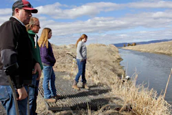 In this March 2, 2020, file photo, farmer Ben DuVal with his wife, Erika, and their daughters, Hannah, third from left, and Helena, fourth from left, stand near a canal for collecting run-off water near their property in Tulelake, Calif.