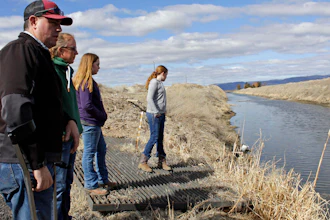 In this March 2, 2020, file photo, farmer Ben DuVal with his wife, Erika, and their daughters, Hannah, third from left, and Helena, fourth from left, stand near a canal for collecting run-off water near their property in Tulelake, Calif.