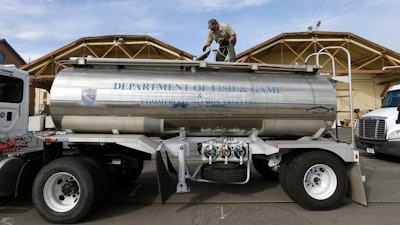In this May 13, 2015 file photo, Rich Cain of the California Department of Fish and Wildlife, prepares a tanker truck filled with young salmon, called 'smolts' to be unloaded into a floating net suspended on a barge at Mare Island, Calif.
