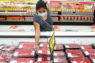In this April 29, 2020 photo, a shopper wears a mask as she looks over meat products at a grocery store in Dallas.