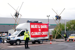 Animal Rebellion protesters suspended from a bamboo structure and on top of a van, being monitored by police officers outside a McDonald's distribution site in Hemel Hempstead, England on May 22.