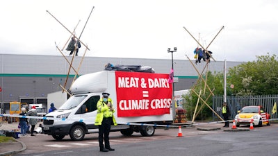 Animal Rebellion protesters suspended from a bamboo structure and on top of a van, being monitored by police officers outside a McDonald's distribution site in Hemel Hempstead, England on May 22.