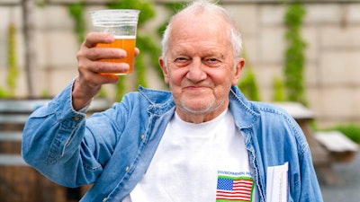 In this May 6 photo, George Ripley, 72, of Washington, holds up his free beer after receiving the J & J COVID-19 vaccine shot at The REACH at the Kennedy Center in Washington.