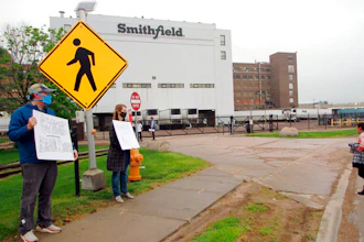 In this May 20, 2020 photo, residents cheer and hold thank you signs to greet employees of a Smithfield pork processing plant as they begin their shift in Sioux Falls, S.D.