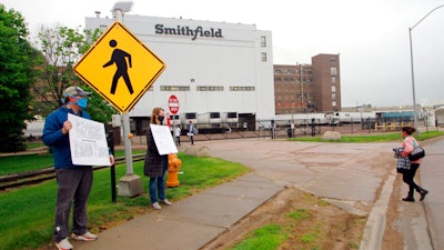 In this May 20, 2020 photo, residents cheer and hold thank you signs to greet employees of a Smithfield pork processing plant as they begin their shift in Sioux Falls, S.D.