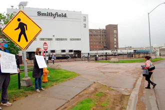 In this May 20, 2020 photo, residents cheer and hold thank you signs to greet employees of a Smithfield pork processing plant as they begin their shift in Sioux Falls, S.D.