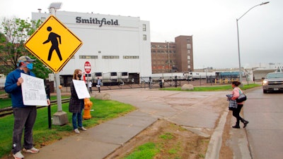In this May 20, 2020 photo, residents cheer and hold thank you signs to greet employees of a Smithfield pork processing plant as they begin their shift in Sioux Falls, S.D.