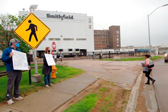 In this May 20, 2020, file photo, residents cheer and hold thank you signs to greet employees of a Smithfield pork processing plant as they begin their shift in Sioux Falls, S.D. Workers at the South Dakota meatpacking plant that became a coronavirus hotspot last year are considering a strike after contract negotiations between Smithfield Foods and the union have stalled, the union said Wednesday, June 2, 2021.