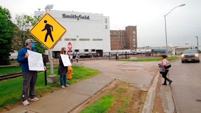 In this May 20, 2020, file photo, residents cheer and hold thank you signs to greet employees of a Smithfield pork processing plant as they begin their shift in Sioux Falls, S.D. Workers at the South Dakota meatpacking plant that became a coronavirus hotspot last year are considering a strike after contract negotiations between Smithfield Foods and the union have stalled, the union said Wednesday, June 2, 2021.