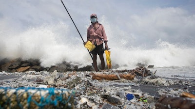 Sri Lankan man, Kindston Jayalath fishes on a polluted beach filled with plastic pellets washed ashore from the fire-damaged container ship MV X-Press Pearl in Kapungoda, on the out skirts of Colombo, Sri Lanka, Friday, June 4, 2021. Authorities were trying to head off a potential environmental disaster as the Singapore flagged ship that had been carrying chemicals was sinking off of the country's main port.