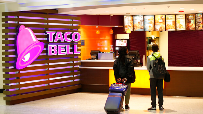 In this April 19, 2019 photo, travelers look at a menu at a Taco Bell restaurant inside Miami International Airport in Miami.