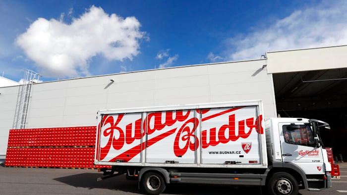 In this file photo taken Monday, March 11, 2019, a truck drives past cases of beer at the Budejovicky Budvar brewery in Ceske Budejovice, Czech Republic. Budvar, the Czech brewer that has been in a long legal dispute with U.S. giant Anheuser-Busch over use of the 'Budweiser' brand, increased its net profit by almost 10% last year amid record output as the pandemic saw people drink less in bars and more at home. Budejovicky Budvar NP, a 125-year-old state-owned brewery, said Monday July 12, 2021, its net profit reached 305 million crowns ($14 million) in 2020.