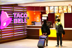 In this April 19, 2019 photo, travelers look at a menu at a Taco Bell restaurant inside Miami International Airport in Miami.