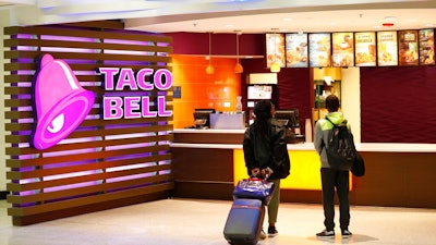 In this April 19, 2019 photo, travelers look at a menu at a Taco Bell restaurant inside Miami International Airport in Miami.
