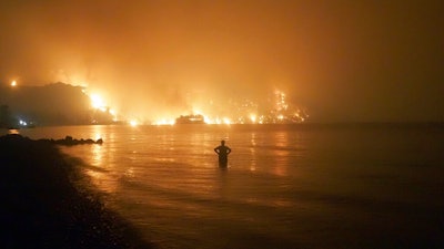 A man watches as wildfires approach Kochyli beach near Limni village, Greece, Aug. 6, 2021.