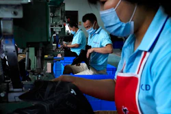 In this July 15, 2021, file photo, workers wearing face masks to help curb the spread of the coronavirus assembly ice-skating shoes at a manufacturing factory in the ice and snow sports equipment industry park in Zhangjiakou in northwestern China's Hebei province. China’s factory activity decelerated in August as export demand weakened, a survey showed Tuesday, Aug. 31, 2021. The monthly purchasing managers’ index of the Chinese statistics bureau and an official industry group declined to 50.1 from July’s 50.4 on a 100-point scale on which numbers above 50 show activity increasing.