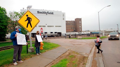 In this May 20, 2020 photo, residents cheer and hold thank-you signs to greet employees of a Smithfield pork processing plant as they begin their shift in Sioux Falls, S.D.