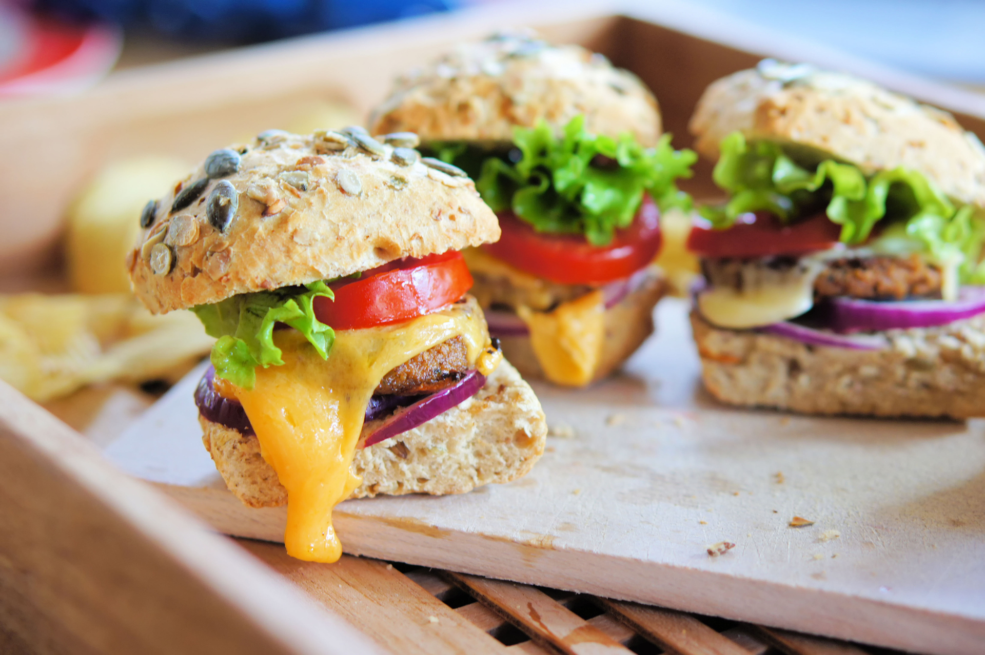 Several small cheeseburger sliders made from worm burger patties. The insect burgers are made from buffalo worms, which are the larvae of the darkling beetle.