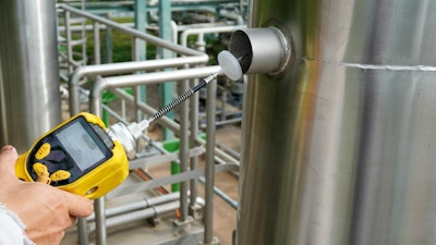 An EPA environmental officer using a chemical detector to test for VOC levels in a factory.