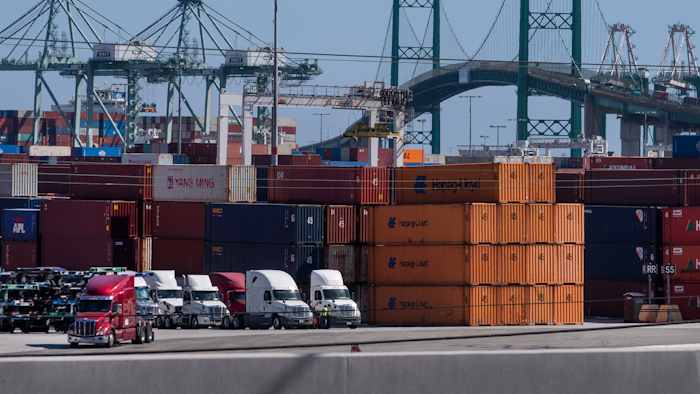 In this Tuesday, Oct. 19, 2021, photo trucks line up next to containers at the Port of Los Angeles in san Pedro, Calif.