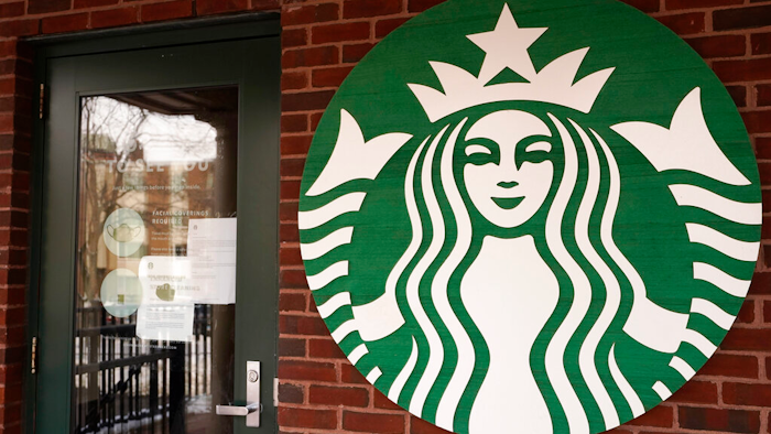 In this Jan. 6, 2021 photo, a Starbucks coffee company logo and information signs are seen at Palatine Metra train station in Palatine, Ill.