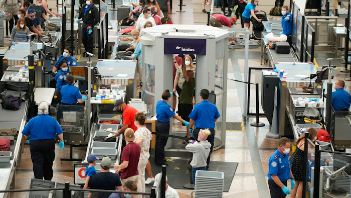 Travelers wear face coverings in the line for the south security checkpoint in the main terminal of Denver International Airport on Aug. 24, 2021, in Denver. The Biden administration is detailing its new international COVID-19 air travel polices, which will include exemptions for kids and new federal contact tracing requirements.