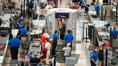 Travelers wear face coverings in the line for the south security checkpoint in the main terminal of Denver International Airport on Aug. 24, 2021, in Denver. The Biden administration is detailing its new international COVID-19 air travel polices, which will include exemptions for kids and new federal contact tracing requirements.