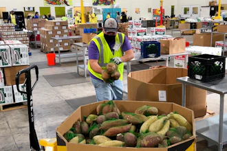 A worker puts bags of sweet potatoes in a container in the warehouse of the Alameda County Community Food Bank in Oakland, CA on Nov. 5, 2021.