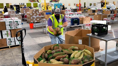 A worker puts bags of sweet potatoes in a container in the warehouse of the Alameda County Community Food Bank in Oakland, CA on Nov. 5, 2021.
