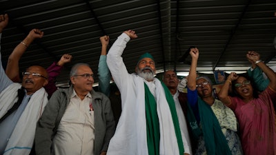Farmer leader Rakesh Tikait , center, and others raise slogans during a rally at Ghazipur, on the outskirts of New Delhi, India on Nov. 26, 2021.