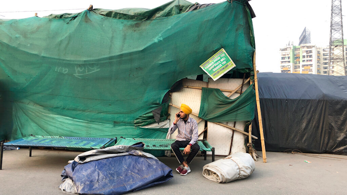 A Sikh farmer talks on the mobile phone as farmers dismantle temporary structures used for their year long protests at Ghazipur, outskirts of New Delhi, India on Dec.9, 2021.