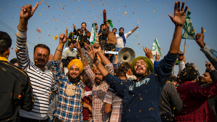 Indian farmers are showered with flower petals as they dance while leaving the protest site in Singhu, on the outskirts of New Delhi, India on Dec. 11, 2021.