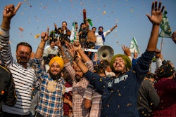 Indian farmers are showered with flower petals as they dance while leaving the protest site in Singhu, on the outskirts of New Delhi, India on Dec. 11, 2021.