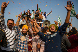 Indian farmers are showered with flower petals as they dance while leaving the protest site in Singhu, on the outskirts of New Delhi, India on Dec. 11, 2021.