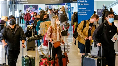Holiday travelers wearing face masks line to check in at the Los Angeles International Airport in Los Angeles on Dec. 22, 2021.