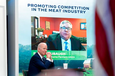 President Joe Biden attends a virtual meeting with family and independent farmers and ranchers including Scott Blubaugh, President, Oklahoma Farmers Union, visible on the monitor, at the South Court Auditorium in the Eisenhower Executive Office Building on the White House Campus in Washington on Jan. 3, 2022 to discuss work to boost competition and reduce prices in the meat-processing industry.