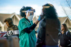 Maya Goode, a COVID-19 technician, performs a test on Jessica Sanchez outside Asthenis Pharmacy in Providence, R.I., Dec. 7, 2021. Scientists are seeing signals that COVID-19′s alarming omicron wave may have peaked in Britain and is about to do the same in the U.S., at which point cases may start dropping off dramatically.