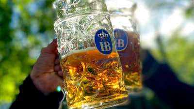People toast with their beer mugs at the 'Taxisgarten' beer garden in Munich, Germany on May 15, 2021.