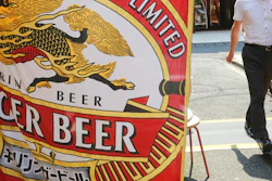 A man walks near an advertisement of a Kirin brand beer in Tokyo on Aug. 25, 2020.
