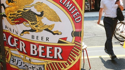 A man walks near an advertisement of a Kirin brand beer in Tokyo on Aug. 25, 2020.
