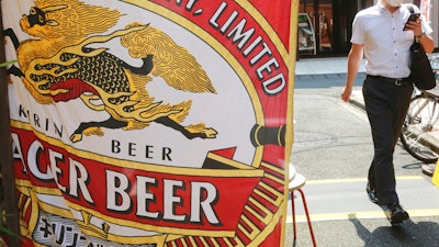 A man walks near an advertisement of a Kirin brand beer in Tokyo on Aug. 25, 2020.